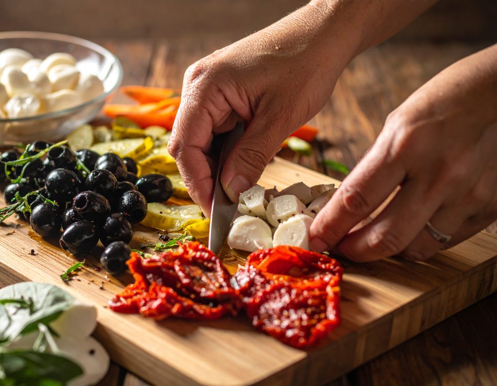 Getrocknete Tomaten und Oliven werden für Caprese-Salat geschnitten
