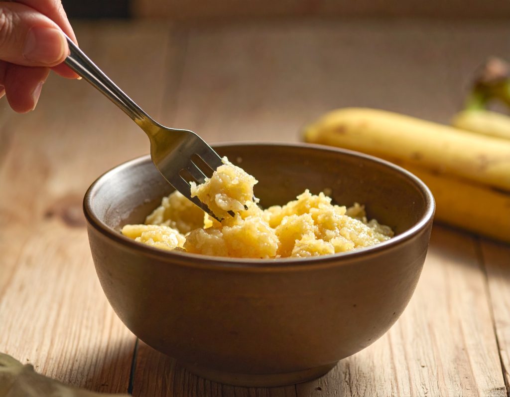 Banane wird unter den Protein-Porridge gerührt